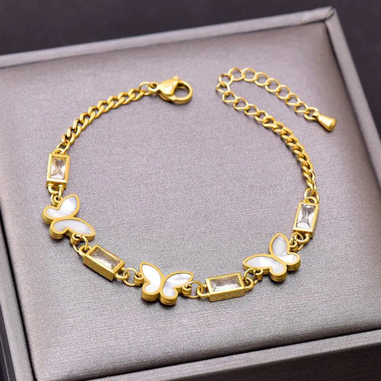 Gold bracelet with butterfly designs on a gray surface