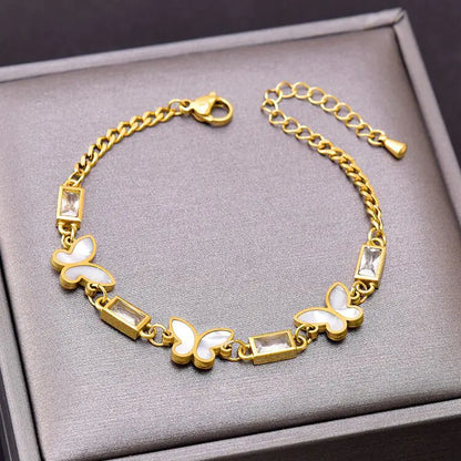 Gold bracelet with butterfly designs on a gray surface